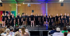 Valmy Academy students performing on stage in theatre black uniforms
